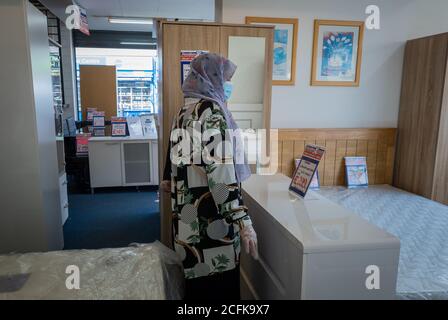 Una donna asiatica sola che indossa la maschera di faccia che acquista in un negozio di mobili. Foto Stock