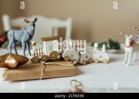 Treno giocattolo bianco e figurine animali posti con presente avvolto In carta artigianale sul tavolo organizzato per la celebrazione di Natale Foto Stock