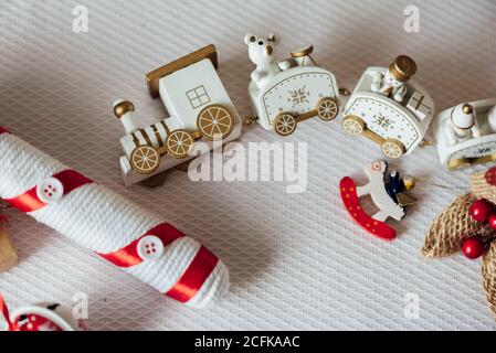 Treno giocattolo bianco e figurine animali posti con presente avvolto In carta artigianale sul tavolo organizzato per la celebrazione di Natale Foto Stock