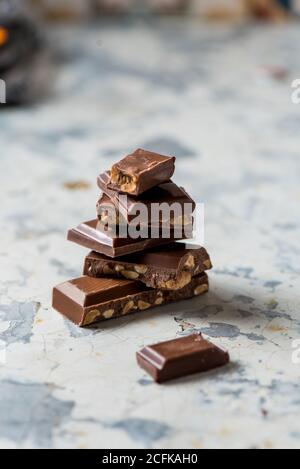 Closeup di pezzi spezzati impilati di barretta di cioccolato con noci posto sul tavolo Foto Stock
