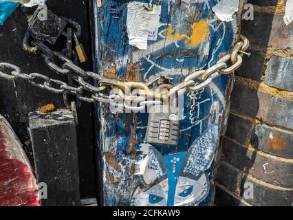 Una catena e un lucchetto combinato su un vecchio cancello e palo di legno. Foto Stock