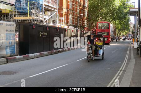 Autista pedicab con tariffa sulla Charing Cross Road di Londra Foto Stock