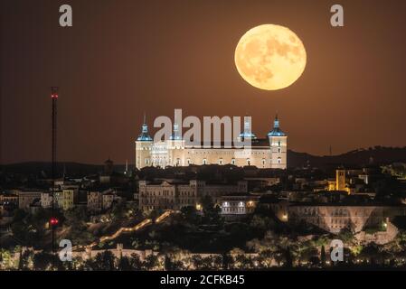 Splendida vista sulla luna piena e luminosa nel cielo notturno scuro sopra la città vecchia con il palazzo storico incandescente Foto Stock