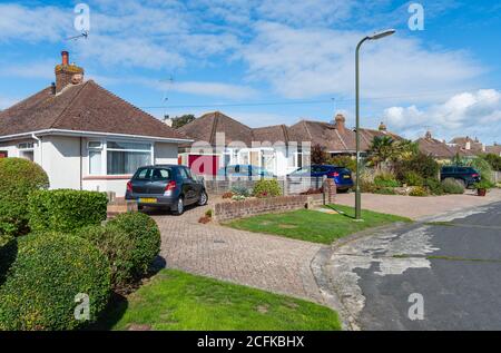 Tranquilla strada residenziale con bungalow, parcheggio fuori strada con strade private. Grandi unità per abitazioni residenziali britanniche nel West Sussex, Inghilterra, Regno Unito. Foto Stock