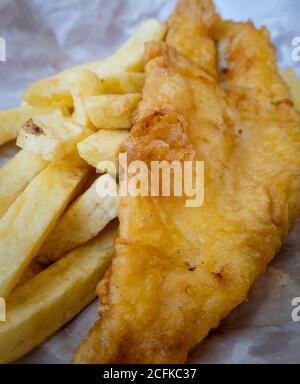 La cucina culturale britannica Pesce e patatine come servito dal negozio di patatine avvolto in carta. Foto Stock