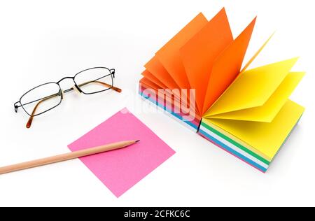 Tampone di carta colorato per note, matita e bicchieri su tavolo bianco, vista dall'alto. Foto Stock