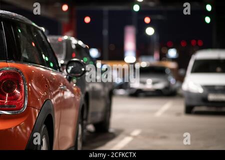 Sfondo, sfocatura, messa a fuoco, bokeh. Lo specchietto laterale della vettura è coperto da gocce di pioggia. L'auto è parcheggiata in un angolo buio del parcheggio Foto Stock