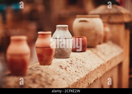 Raccolta di varie pentole di ceramica fatte a mano poste in fila sopra recinzione di pietra sul mercato locale dei souvenir Foto Stock