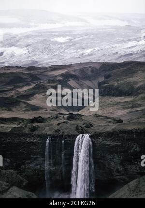 Cascata Seljalandsfoss in una giornata nordica buia e moody con neve fresca Foto Stock