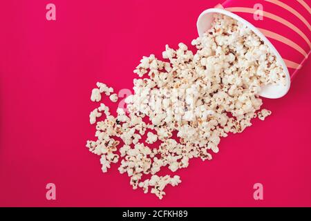 Tazza con popcorn su sfondo di colore rosa Foto Stock