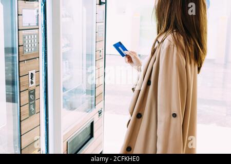 donna usa la sua carta di credito per pagare al distributore macchina Foto Stock