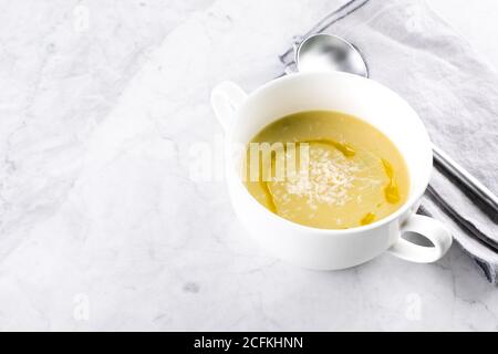 Zuppa di crema di zucchine con latte di cocco in ciotola su sfondo chiaro del tavolo in marmo. Foto Stock
