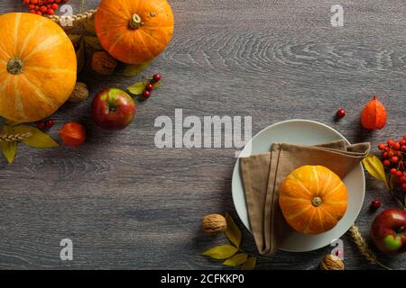 Stagione di ringraziamento ancora vita con zucche mature, piatto e frutti autunnali su tavola rustica di legno. Disposizione piatta, vista dall'alto, spazio per la copia Foto Stock