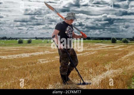 Cercare il tesoro sul campo con un dispositivo e. una pala Foto Stock