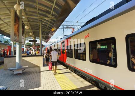 Sochi, Krasnodar Krai, Russia - Giugno 09.2017: I passeggeri camminano lungo la piattaforma passando i treni pendolari alla stazione ferroviaria di Sochi Foto Stock