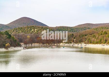 Russia, regione di Krasnodar, Sukko - Novembre 19.2017: Persone che navigano intorno ai cipressi paludosi e camminano lungo la riva di un lago tra i montai Foto Stock