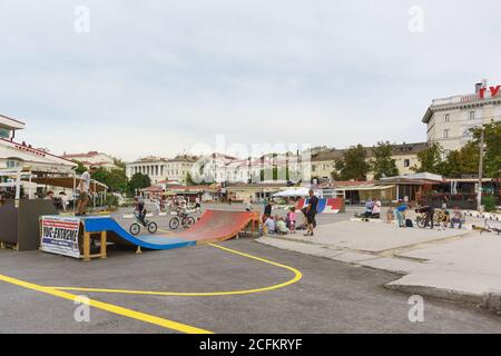 Russia, Crimea, Sevastopol - Settembre 06.2017: La sera d'estate dei ragazzi ride skateboards e biciclette per le strade della città Foto Stock
