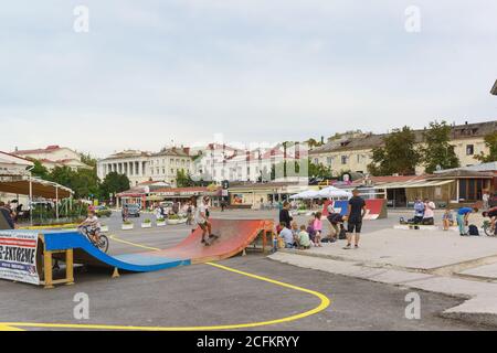 Russia, Crimea, Sevastopol - Settembre 06.2017: La sera d'estate dei ragazzi ride skateboards e biciclette per le strade della città. L'area del tercentenario del Th Foto Stock