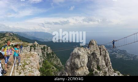 Mishor, Yalta, Crimea, Russia - 14 settembre 2018: Donne e uomini camminano su un ponte di corda teso tra i denti del monte ai-Petri. Popolare turista Foto Stock