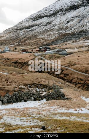 Casa residenziale in legno in insediamento in autunno sulle Isole Faroe sulle montagne innevate Foto Stock