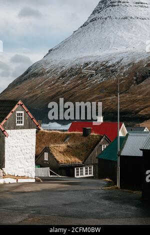 Casa residenziale in legno in insediamento in autunno sulle Isole Faroe sulle montagne innevate Foto Stock