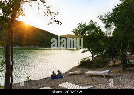 Lago di Sukko, regione di Krasnodar, Russia - 06 luglio 2019: Le persone si rilassano sulla riva dopo il bagno nel lago di Cypress. Tramonto Foto Stock