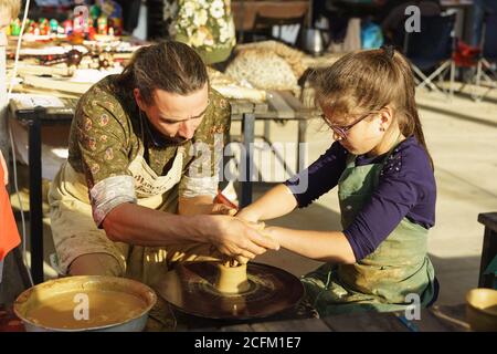 Moldavanskoye, Krymsk, Russia-05 Ottobre 2019: Un vasaio insegna ad una ragazza come fare una brocca di argilla gialla. Master class al festival del vino giovane di le Foto Stock