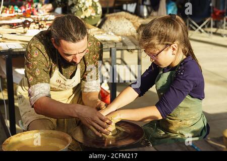 Moldavanskoye, Krymsk, Russia-05 Ottobre 2019: Un vasaio insegna ad una ragazza come fare una brocca di argilla gialla. Master class alla festa del vino giovane in Foto Stock