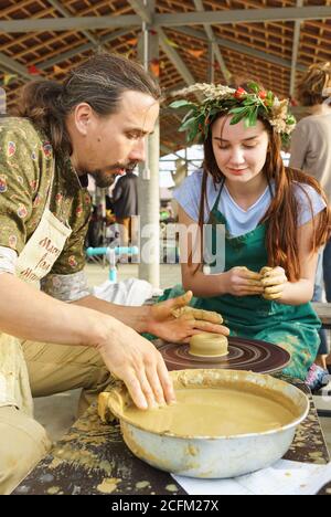 Moldavanskoye, Krymsk, Russia-05 ottobre 2019: Un artigiano mostra a una ragazza come fare una caraffa da argilla su una ruota di Potters. Master class al festi Foto Stock