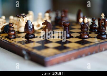 Pezzi di scacchi su tavola di gioco in legno. I pezzi includono la pedina, il re, la regina, il vescovo, il cavaliere e il rook Foto Stock