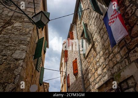 Stari grad/Croazia-5 agosto 2020: Magnifiche stradine strette tra case in pietra con persiane in legno e la bandiera croata appeso nella Stari Grad a. Foto Stock
