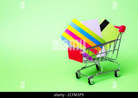 il mockup della carta di credito in molti colori è messo nel carrello rosso dello shopping su sfondo giallo, concetto di affari usando le carte di credito senza contanti che è facile Foto Stock