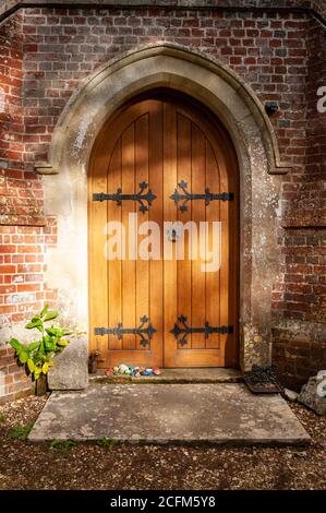 Porta d'ingresso in legno ad arco della chiesa di St Leonards 13 ° secolo nel villaggio rurale di Whitsbury, Hampshire, Regno Unito Foto Stock