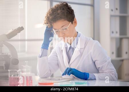 Scienziato o ricercatore contemporaneo che guarda attraverso i dati online in un tablet Foto Stock