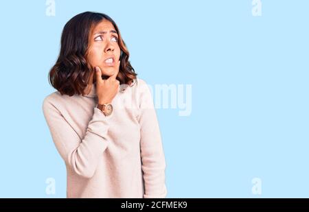 Giovane bella razza mista donna con maglione invernale a dolcevita pensando preoccupato per una domanda, preoccupato e nervoso con la mano sul mento Foto Stock
