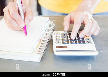 Mano che tiene la penna e premendo i pulsanti di calcolatrice, stock photo Foto Stock