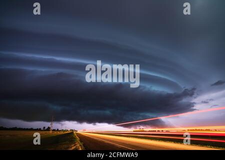 Tempesta di Supercelle e strada con nubi di tempesta scure e drammatiche illuminate da un fulmine vicino a Ford, Kansas Foto Stock