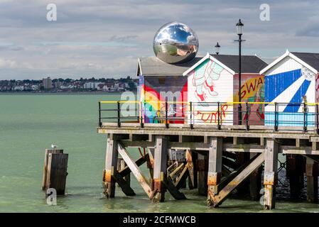 Capannoni dai colori vivaci alla fine di Southend Pier, Southend on Sea, Essex, Regno Unito. Capanne luminose sul molo con palla a specchio che riflette cielo e mare Foto Stock