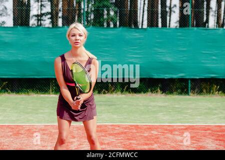 Donna tennista professionista focalizzata in posizione pronta. Una atleta in attesa di servire. Sfida e concentrazione nella concorrenza. Foto Stock
