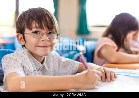 felice ragazzino che studia in classe Foto Stock