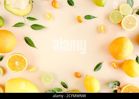 Cornice fatta di frutti tropicali estivi: Arancio, limone, lime, mango su sfondo giallo. Concetto alimentare. Disposizione piatta, vista dall'alto Foto Stock