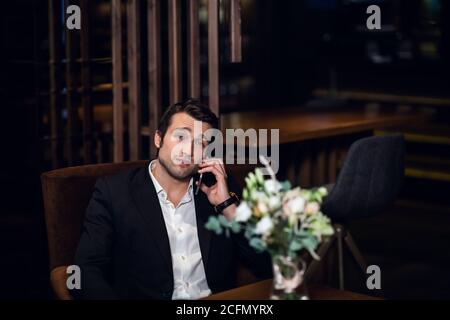 bell'uomo che parla al telefono, seduto a un tavolo da bar. Foto Stock