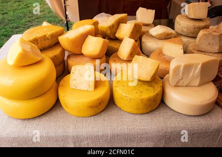 Formaggi naturali. Molte teste di formaggio sul tavolo ricoperte di tela di lino. Un bancone con teste di formaggio alla fiera. Vendita di fattoria narurale duro che Foto Stock