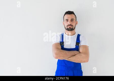 Un costruttore in una tuta blu si erge con le braccia ripiegate sul petto Foto Stock