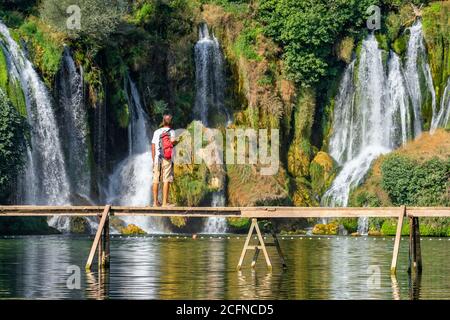 Il turista non identificato sorge sul ponte di legno di fronte Bella cascata di Kravica in Bosnia Erzegovina Foto Stock