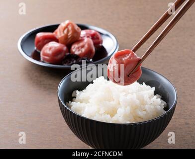Prugne sottaceto giapponese e riso cotto al momento con un pezzo di prugne sottaceto con chopsticks Foto Stock