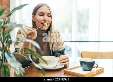 Giovane donna bionda sorridente in abbigliamento casual con pranzo a. il caffè Foto Stock