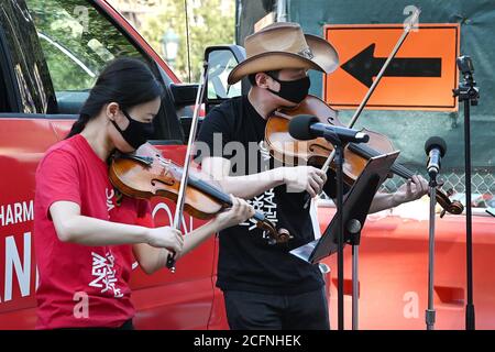 Il violinista Filarmonico di New York Quan GE e l'assistente principale viola Cong Wu si esibiscono fuori dall'ingresso dei Giardini Botanici di Brooklyn come parte dei concerti pop-up dei carri a bandwagon di NY Phil nel quartiere Brooklyn di New York, NY, 6 settembre 2020. Con i locali di musica ancora chiusi a causa delle restrizioni pandemiche della COVID-19, la New York Philharmonic ha creato uno spettacolo "pull-up" in tutti i cinque quartieri di New York City, ma non fornisce alcun preavviso per ridurre al minimo le dimensioni della folla e il rischio di diffondere il coronavirus. (Anthony Behar/Sipa USA) Foto Stock