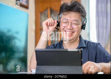 Uomo asiatico di mezza età che lavora a casa. Concetto di telelavoro. Foto Stock
