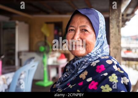 Bandar seri Begawan / Brunei - 16 gennaio 2019: Primo piano ritratto di donna musulmana con sciarpa di testa sorridente a macchina fotografica in casa di legno a Kampong Ayer villaggio galleggiante Foto Stock